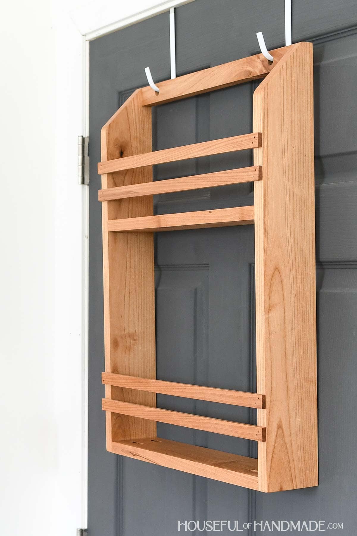 Wood shelf unit with 2 shelves hanging on hooks on a door. 